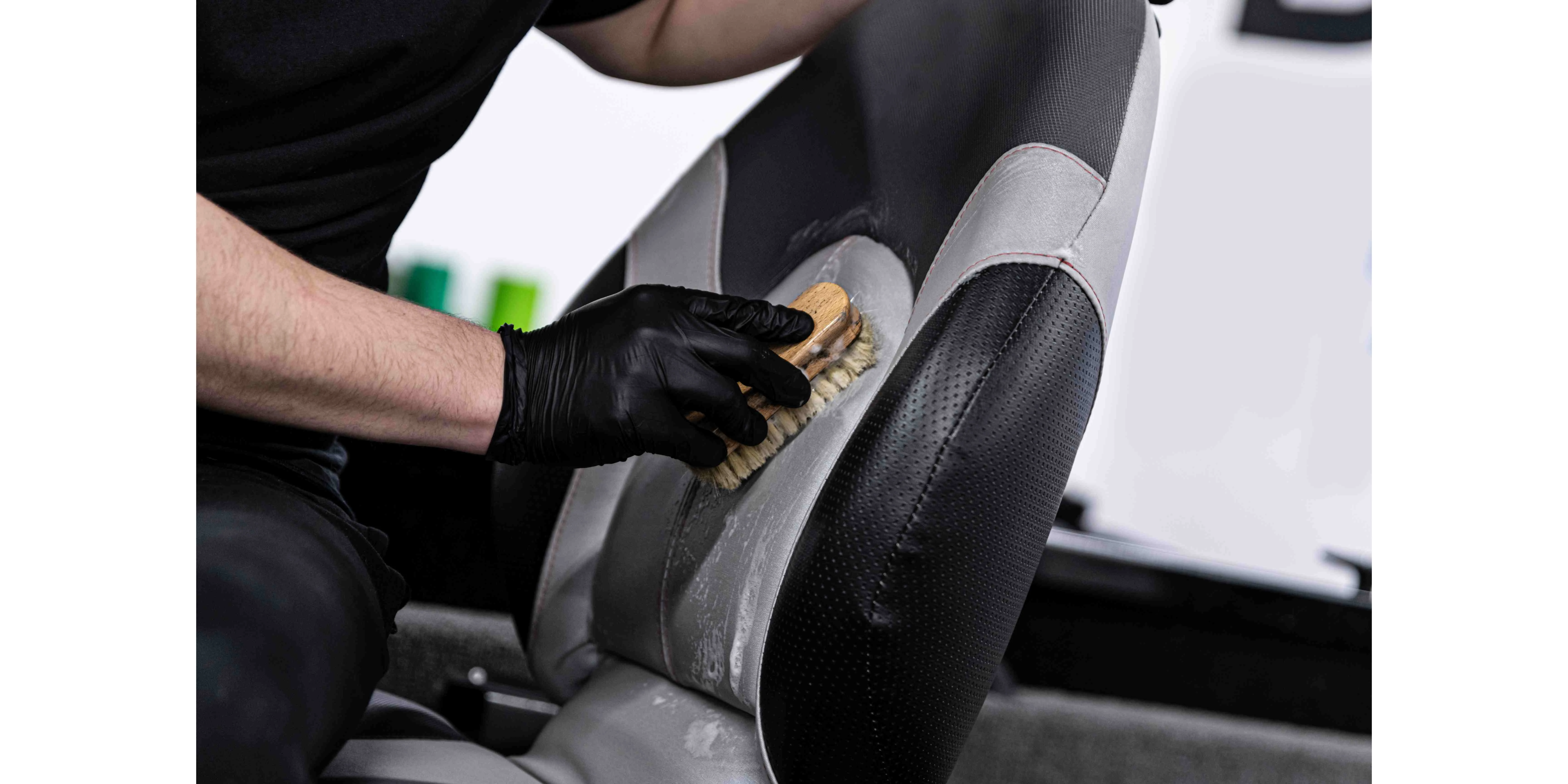 man car wash worker cleaning leather boat seat with brush