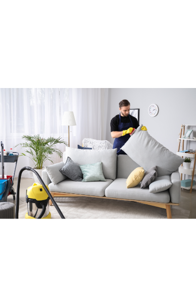 male janitor cleaning sofa in a room