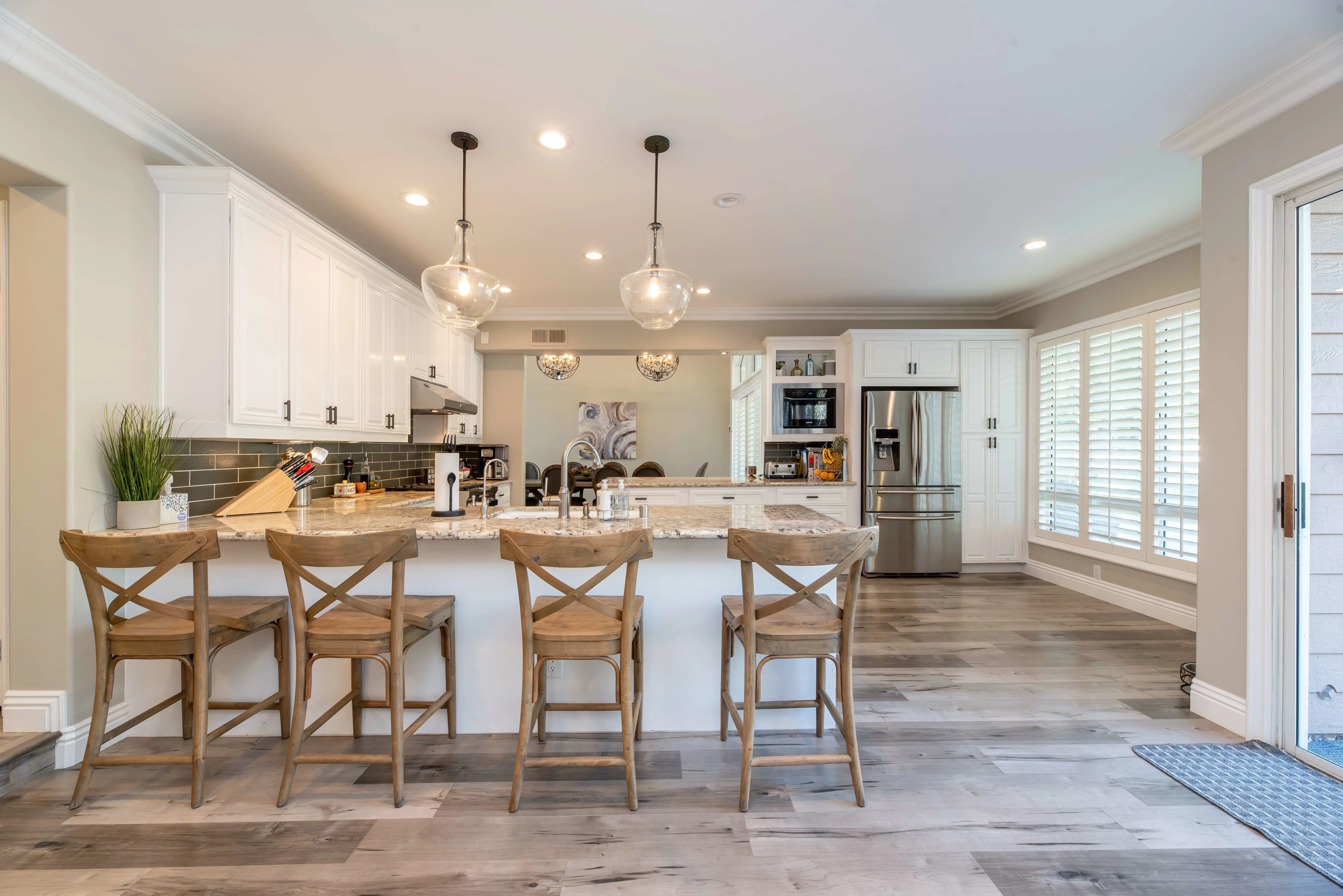 Picture of a clean kitchen area with hanging lights and bar stools 