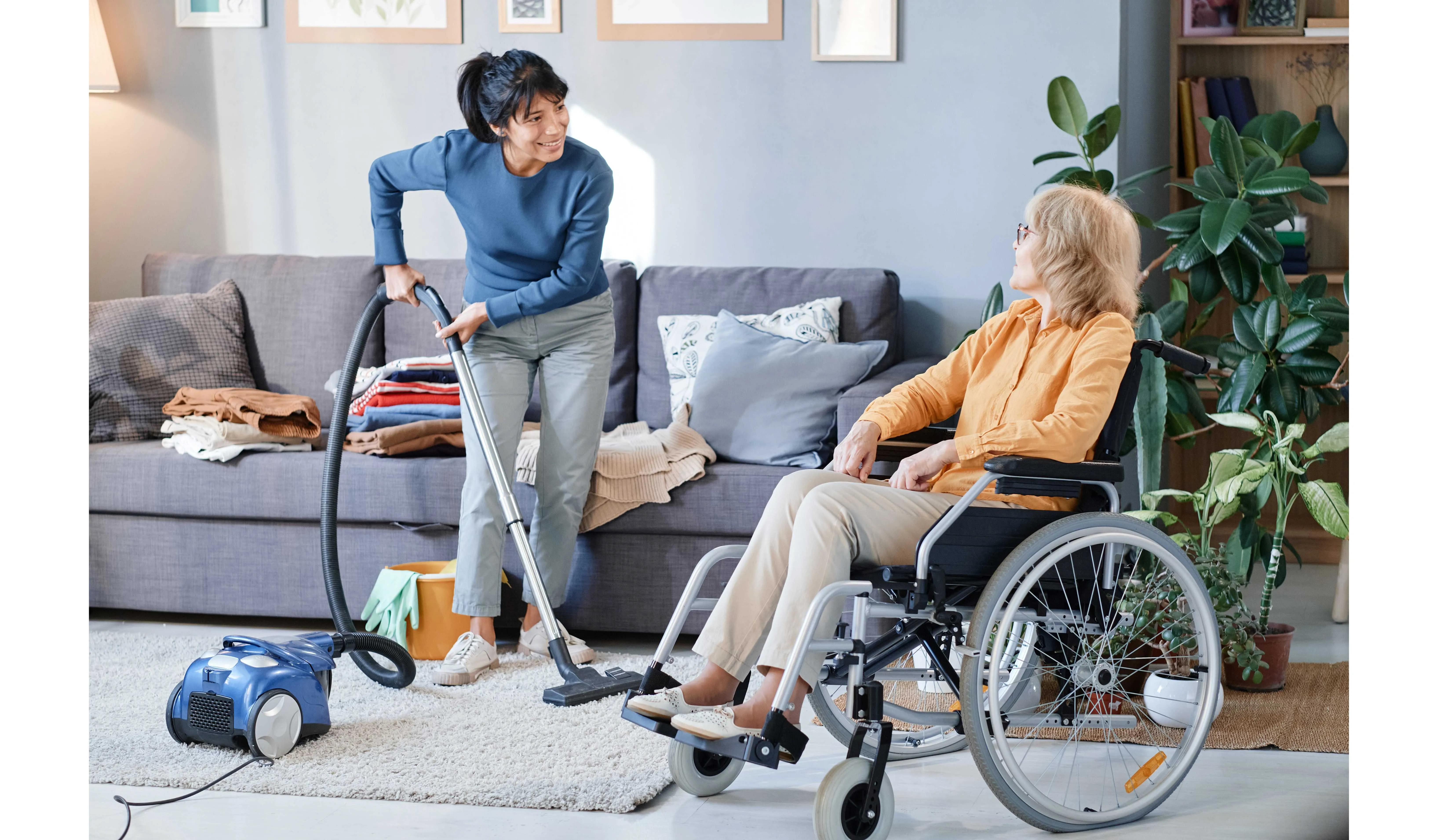 a cleaner cleaning while a woman in a wheelchair talks to her