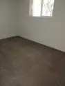 A professional maid in a neat uniform dusting a shelf in a cozy, well-lit living room with cleaning supplies nearby, highlighting clean maid services