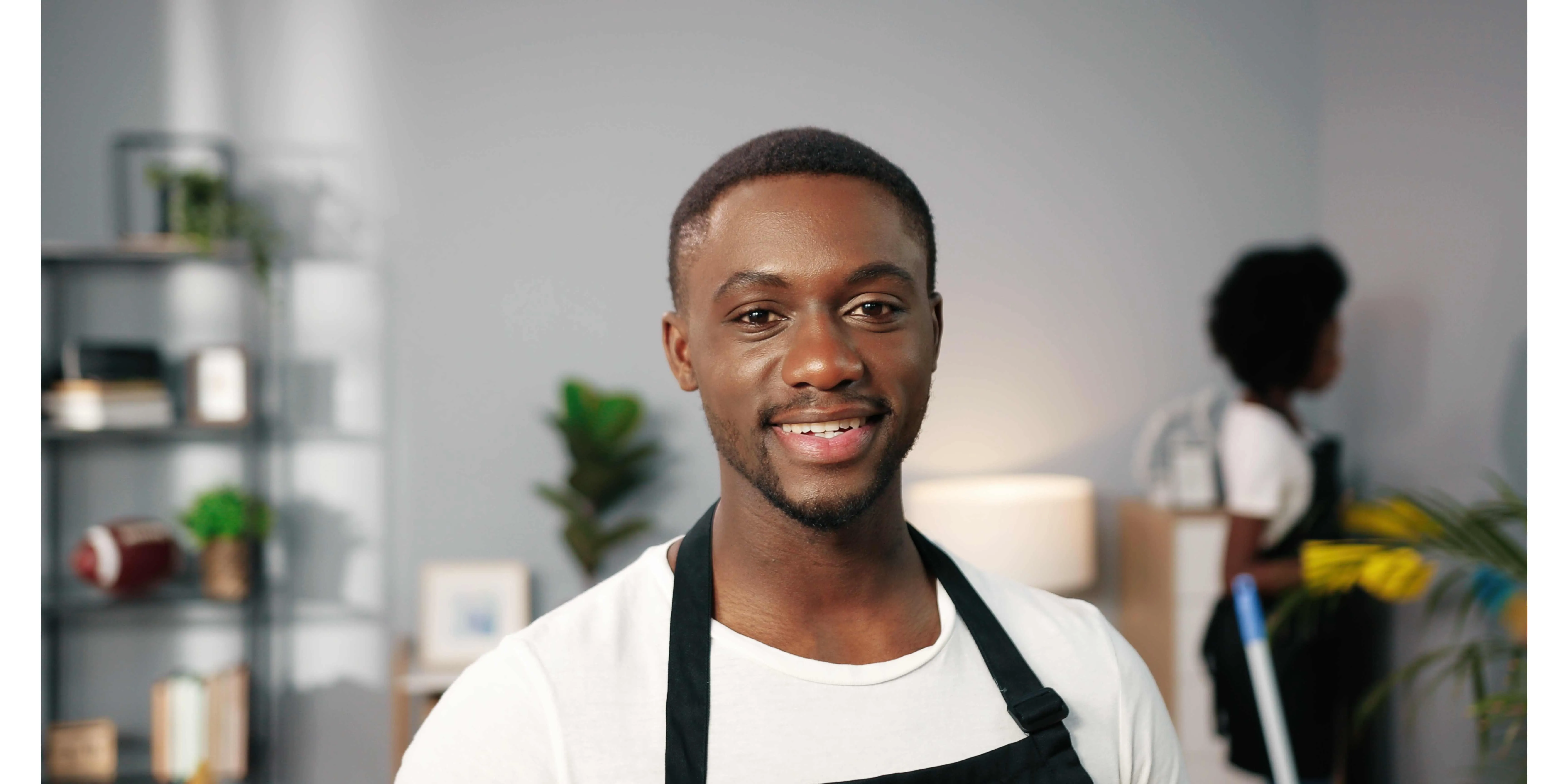 male house cleaner smiling and cleaning a home