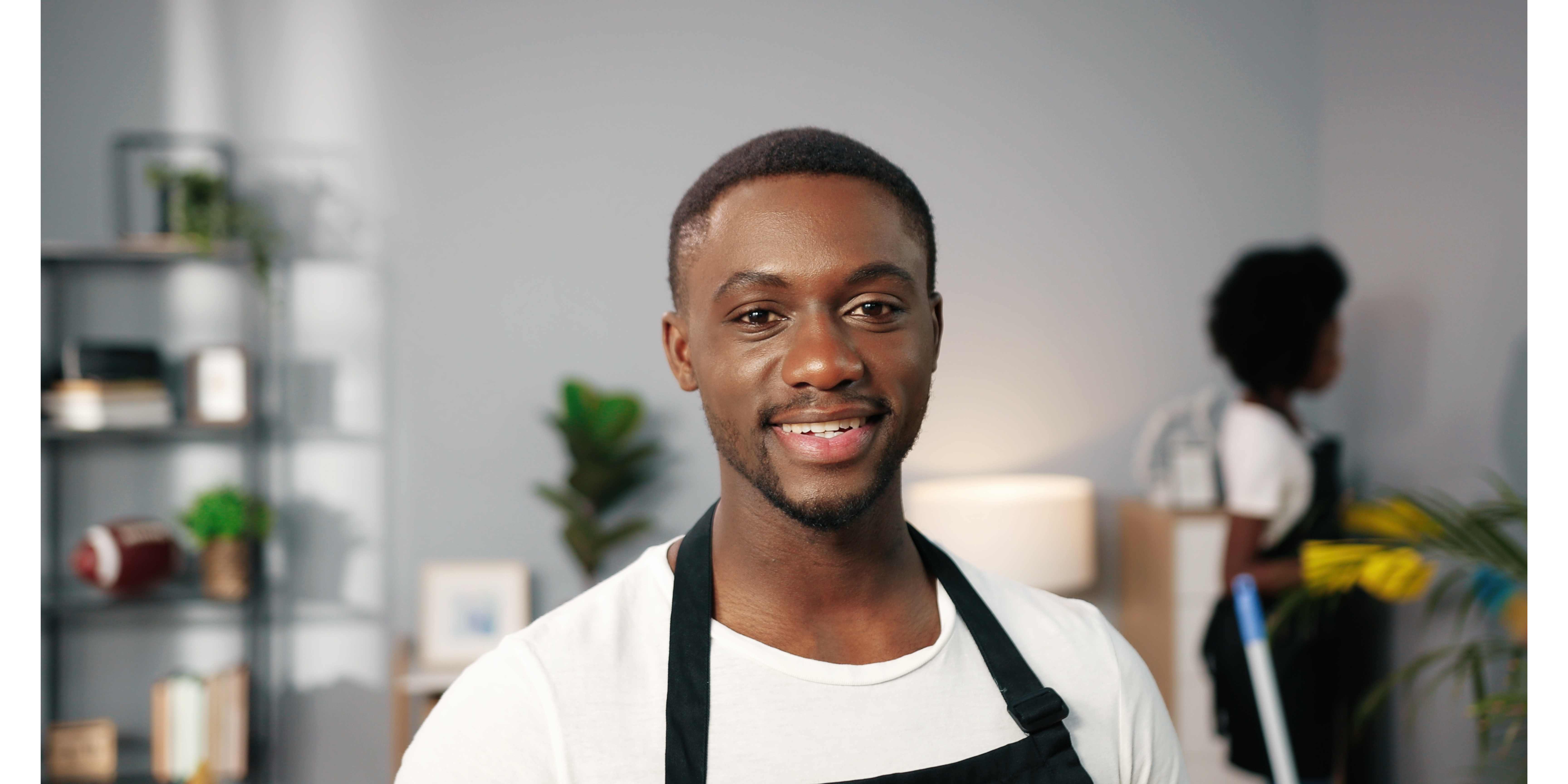 male house cleaner smiling and cleaning a home